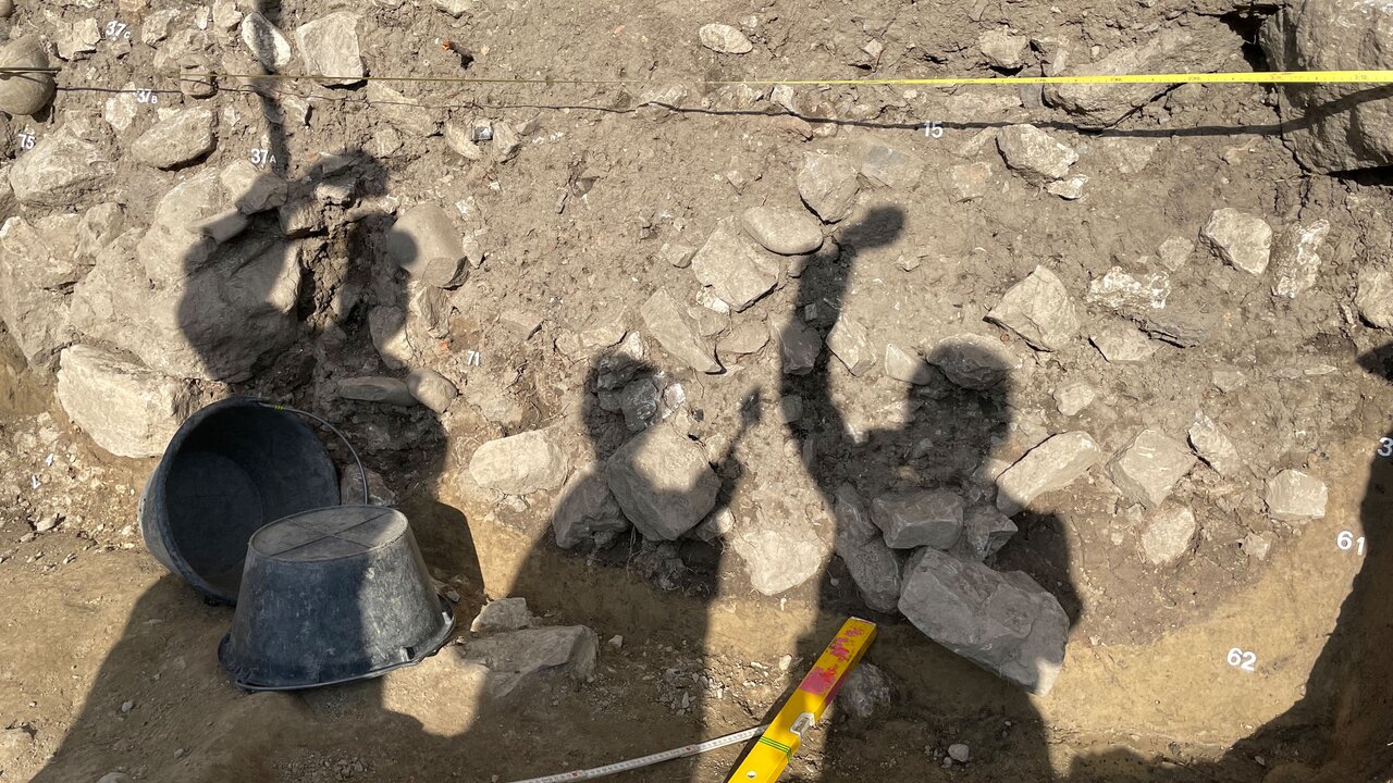 Schattenwürfe von drei Personen werden gezeigt, um aufzuzeigen, dass die Ausgrabungen eine Teamarbeit ist. 